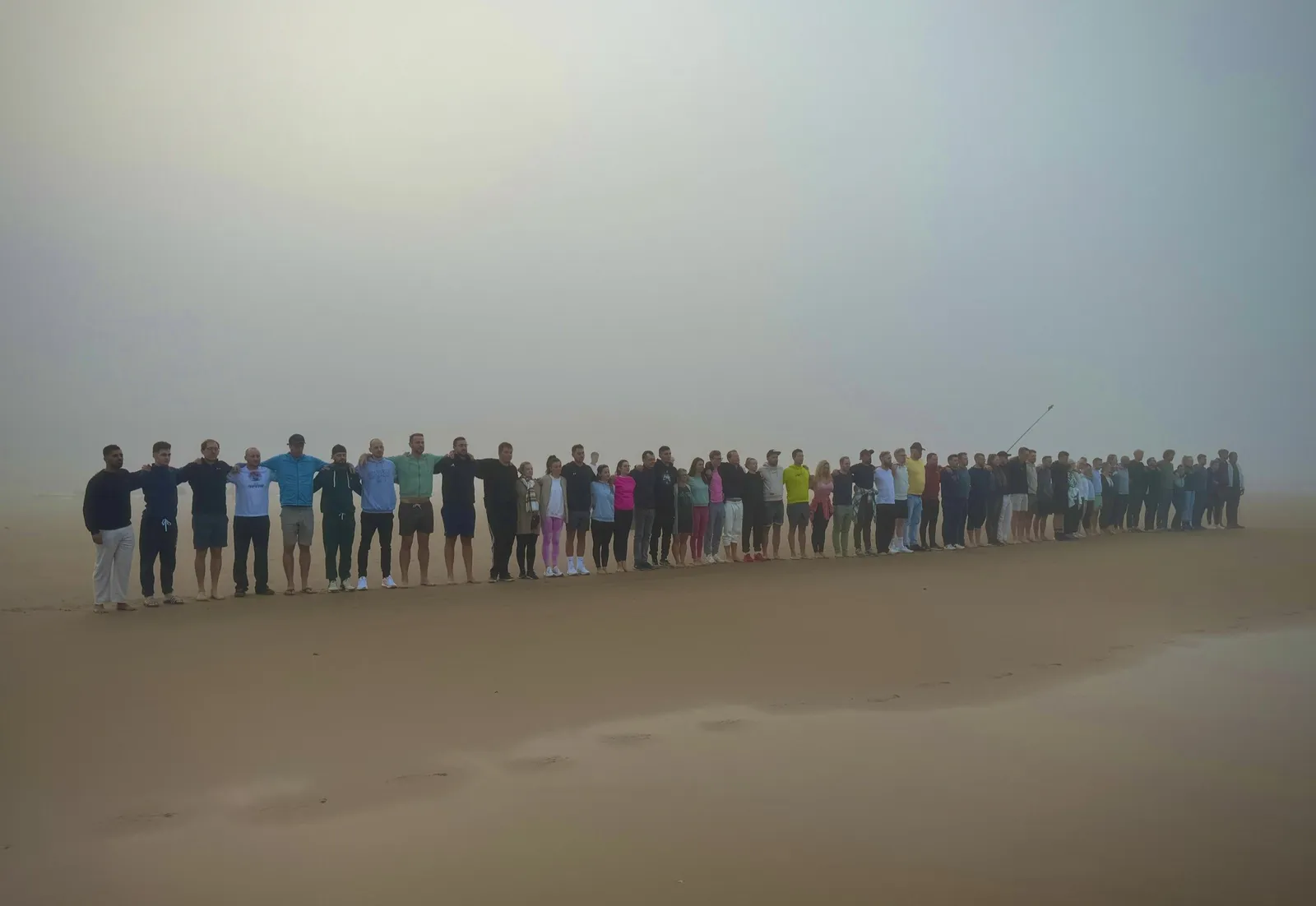Menschenkette am Strand im Morgennebel